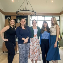The friendly staff smiling and standing together at Chorus at Asheville senior living apartments in Asheville, NC.