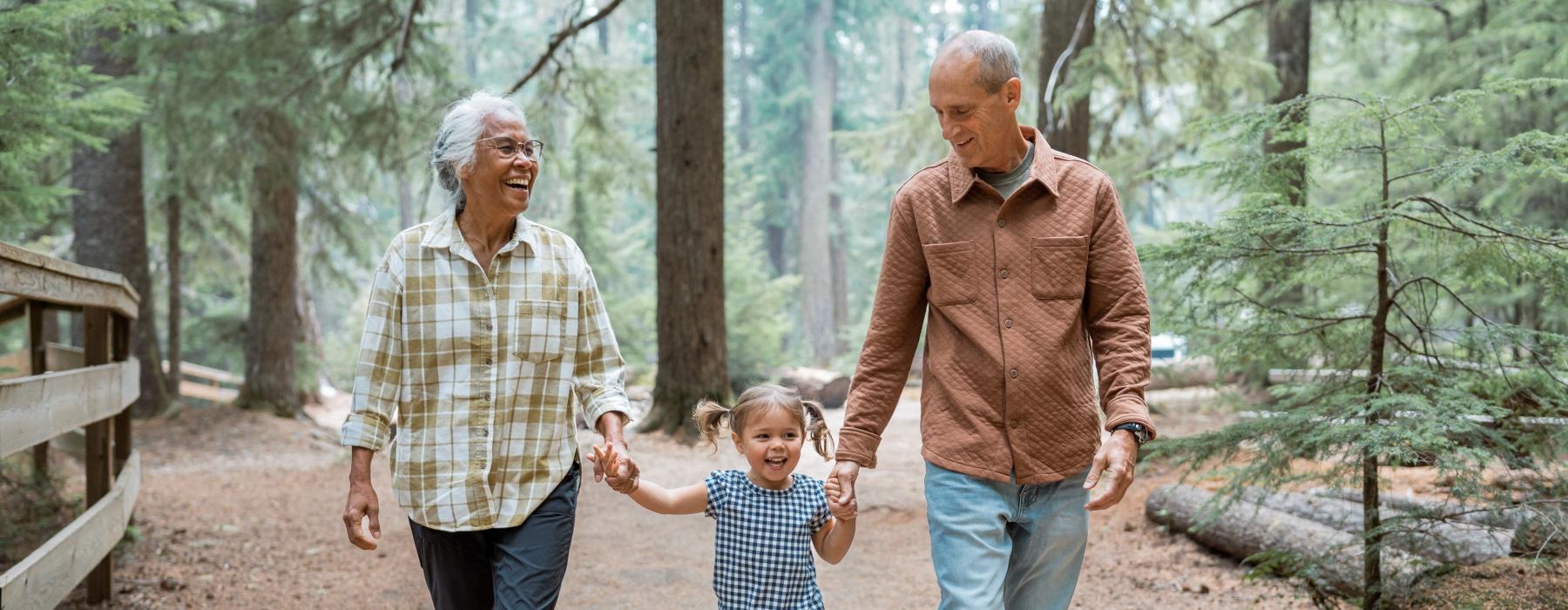 grandparents walk through the forest with granddaughter